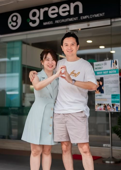 Green Employment founders making a G hand gesture outside their maid agency office in Singapore.
