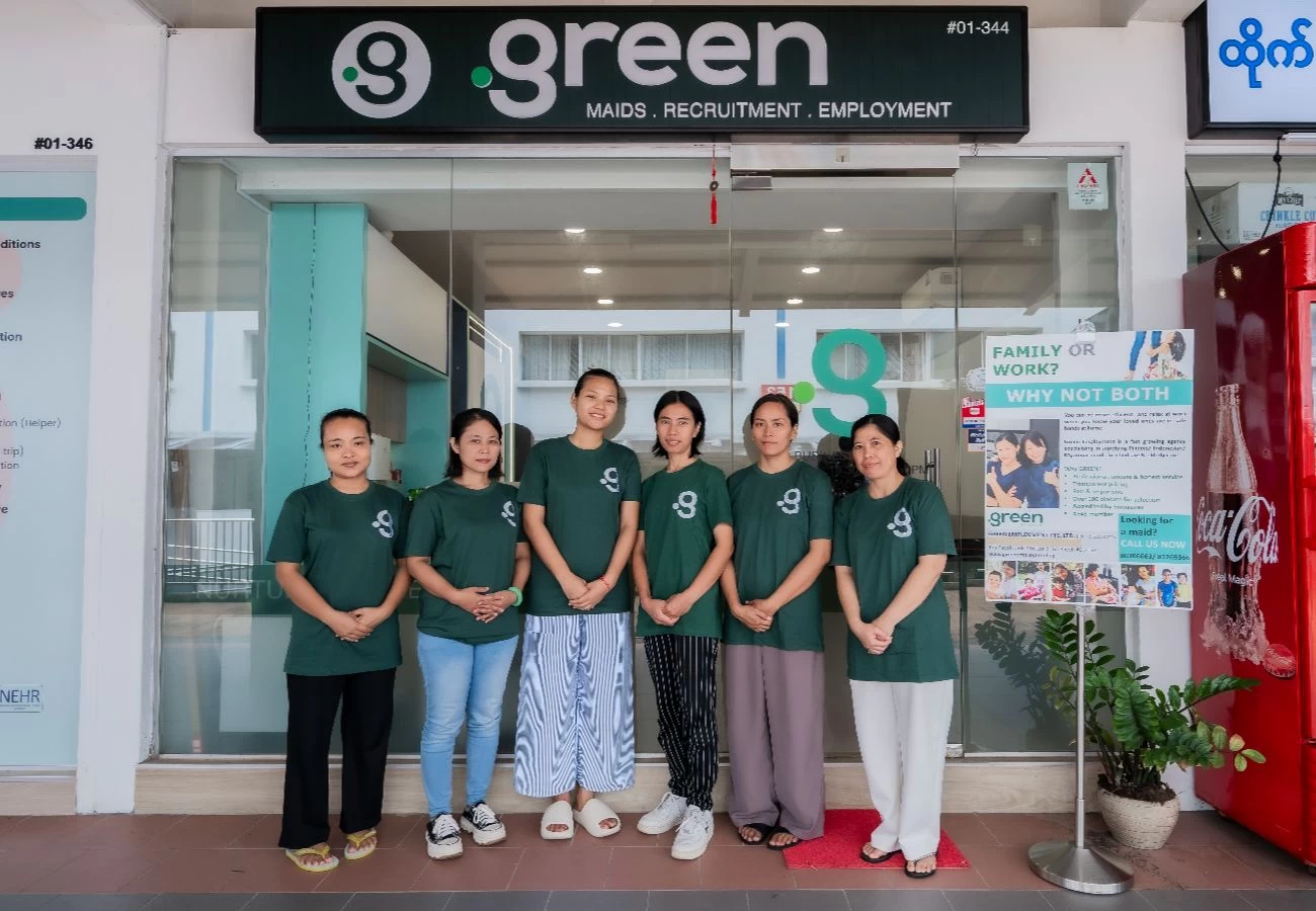 A group of domestic helpers stands outside the Green Employment maid agency office.