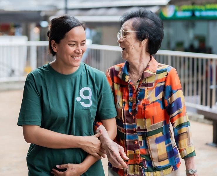 Caregiver walking with elderly woman in a public area